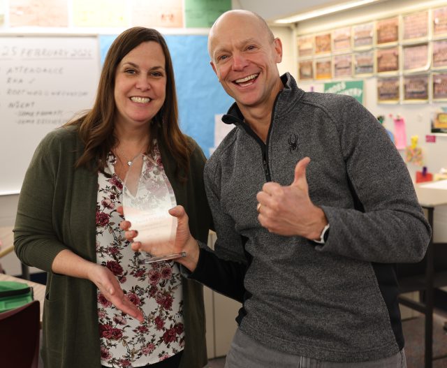 Woman and man holding award smiling