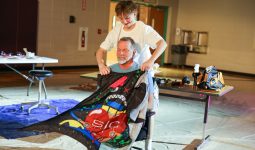 Two people working together to fold a colorful quilt.
