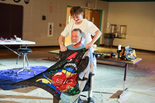 Two people working together to fold a colorful quilt.