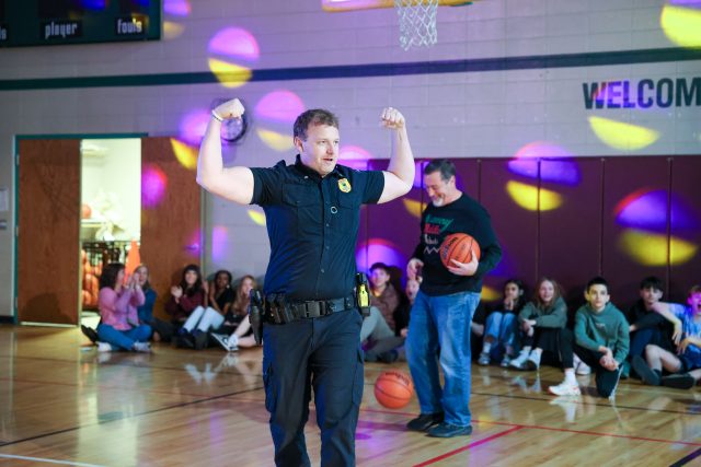 Police officer in gymnasium holding basketball.