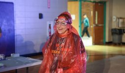 Woman in a red rain poncho standing at a table.