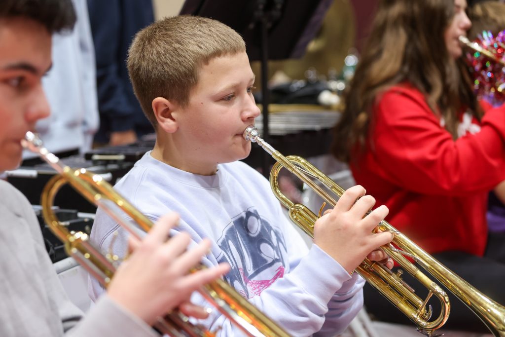 Two young boys playing trumpets in a band.